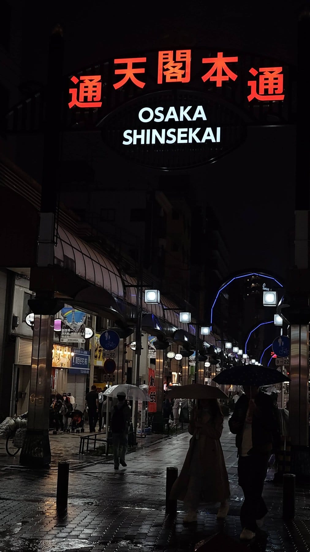 Osaka Shinsekai arcade entrance glowing at night in the rain