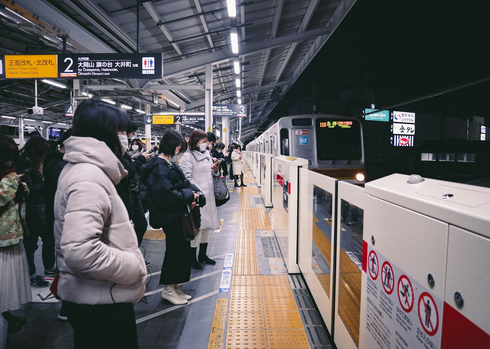 Travellers waiting for a train on a Tokyo station platform