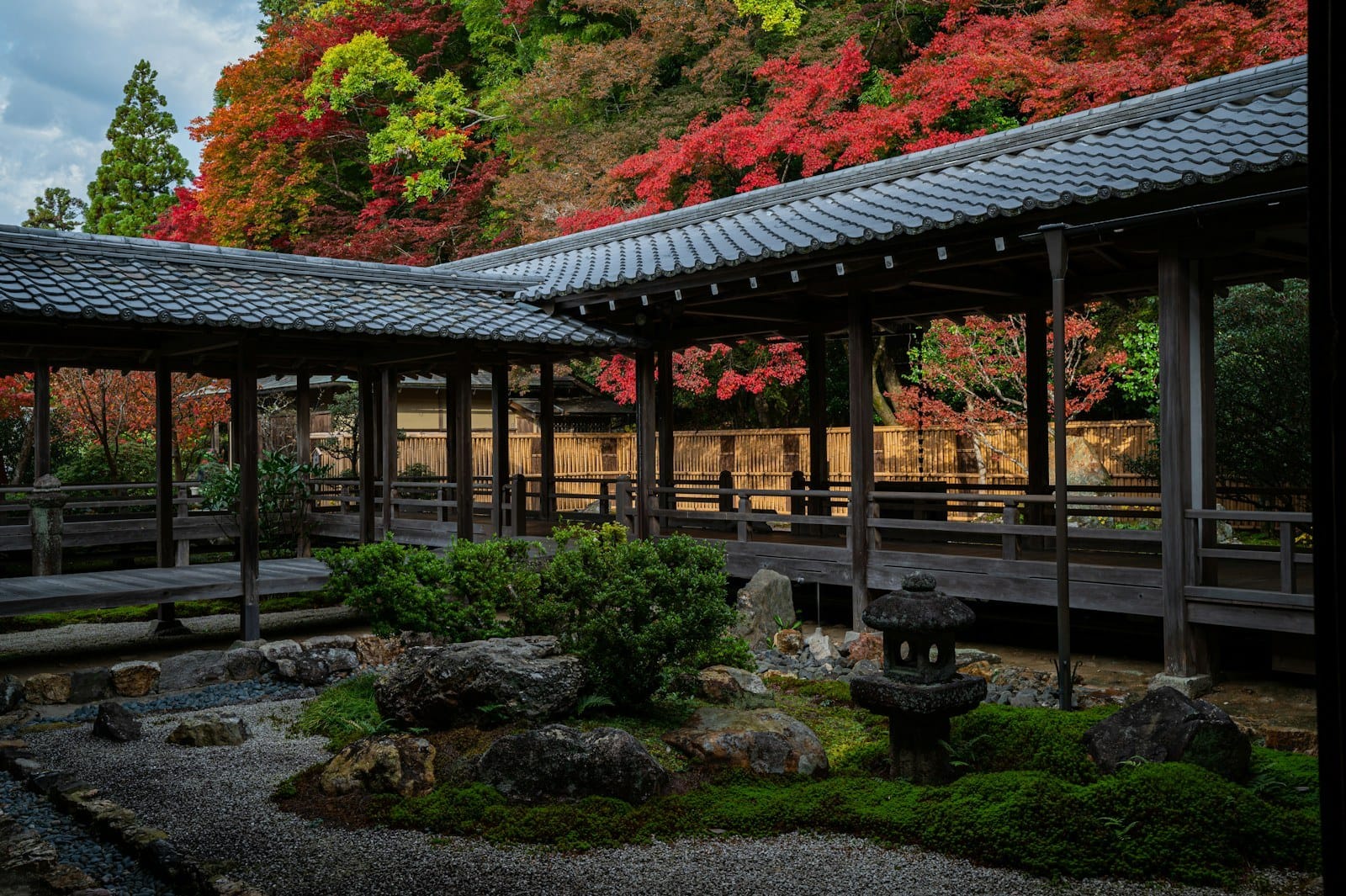 A traditional wooden walkway overlooking a Kyoto garden with autumn foliage.