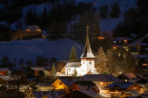 A snowy Swiss village at night with a lit church