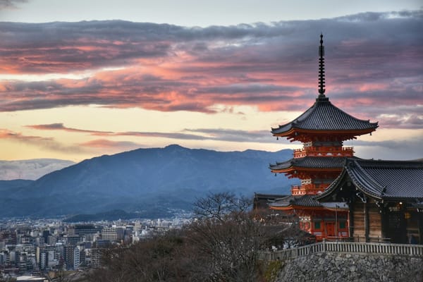 Kiyomizu-dera pagoda in Kyoto at sunset, with the city and mountains behind it
