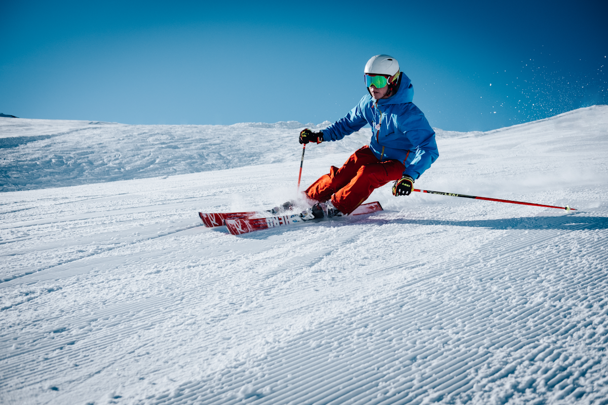 Cable car ascending snowy mountains with skiers visible on slopes below at Shymbulak ski resort